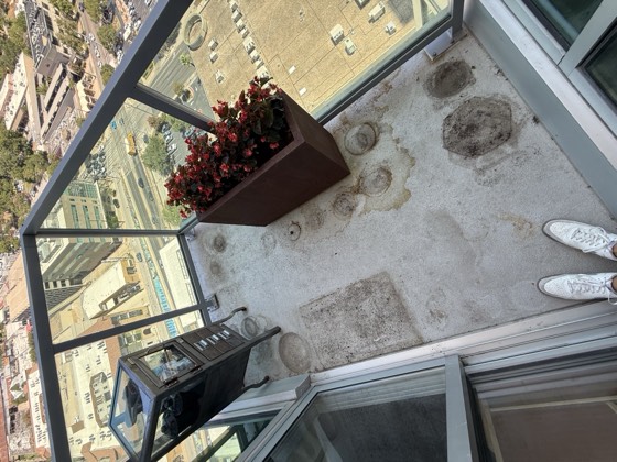 Balcony before cleaning &mdash; dark ring stains from planters and ground-in dirt across the concrete floor.