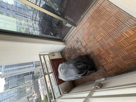 Balcony before cleaning &mdash; wood deck tiles dulled to a flat grey-brown, with darkened patches across the boards.